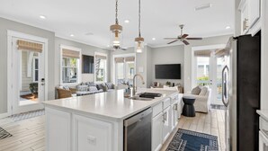 A spacious kitchen with a large island, white cabinetry, and a built-in dishwasher.