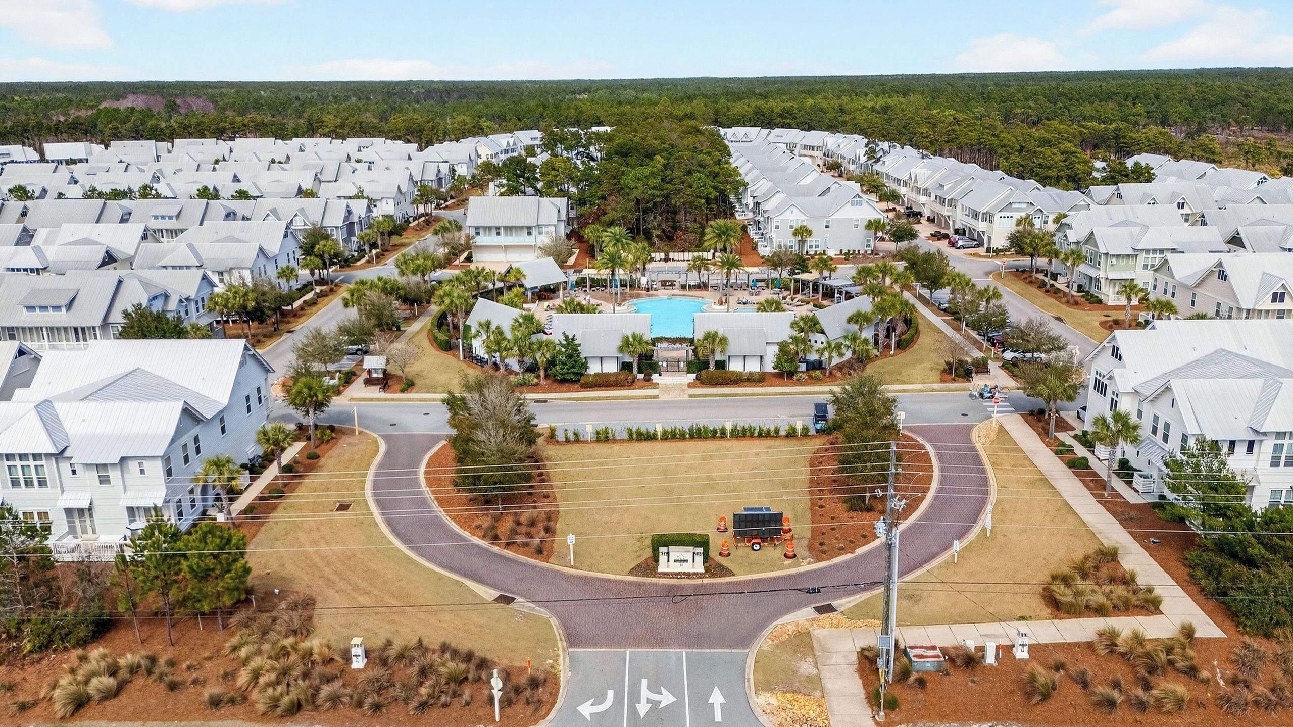 A residential area with multiple houses, a central swimming pool, and a curved road layout.