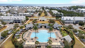 A resort with a central swimming pool, multiple guest villas, and a view of the ocean.