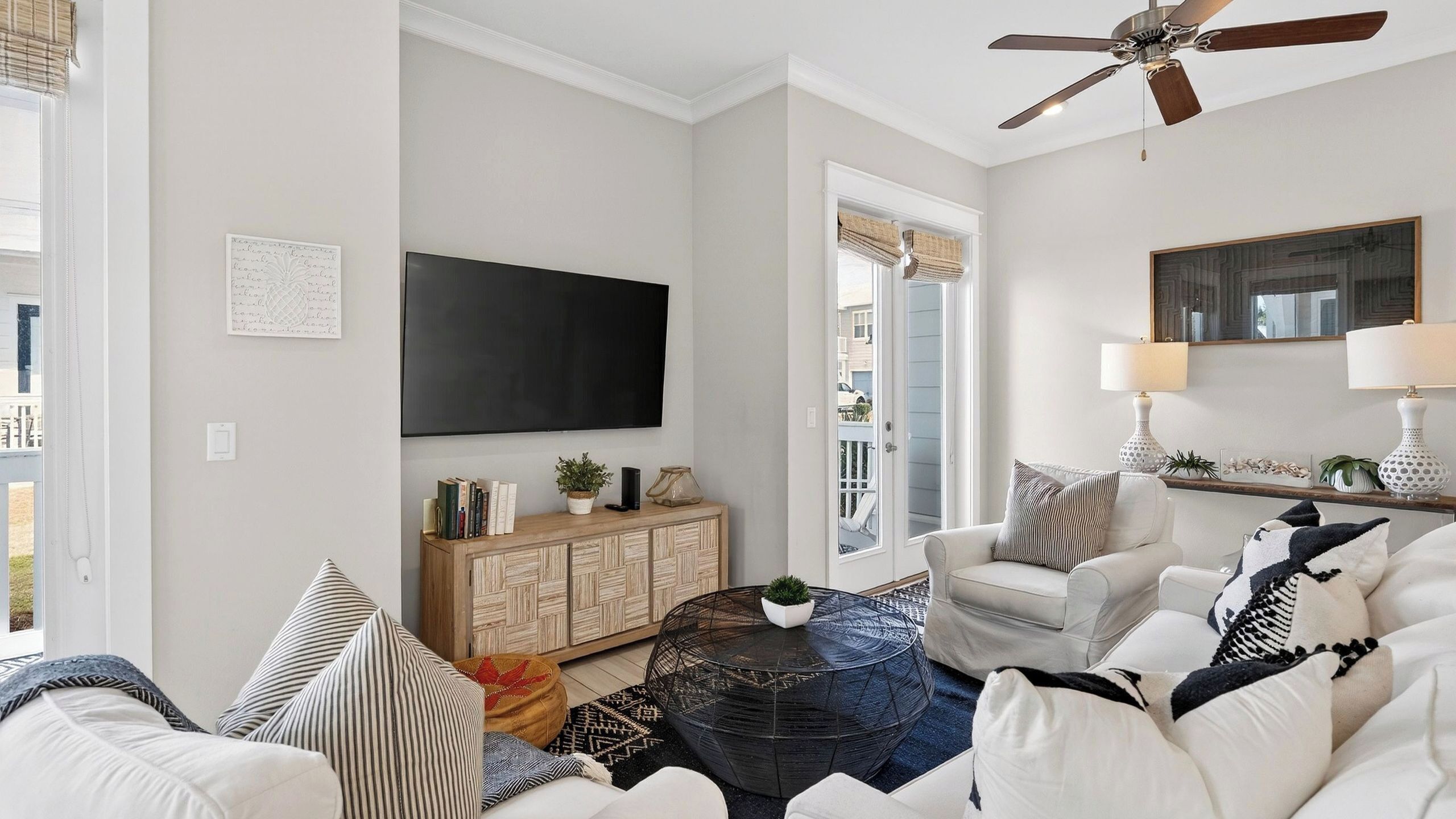 A living room with a sofa, armchair, coffee table, and a TV mounted on the wall.