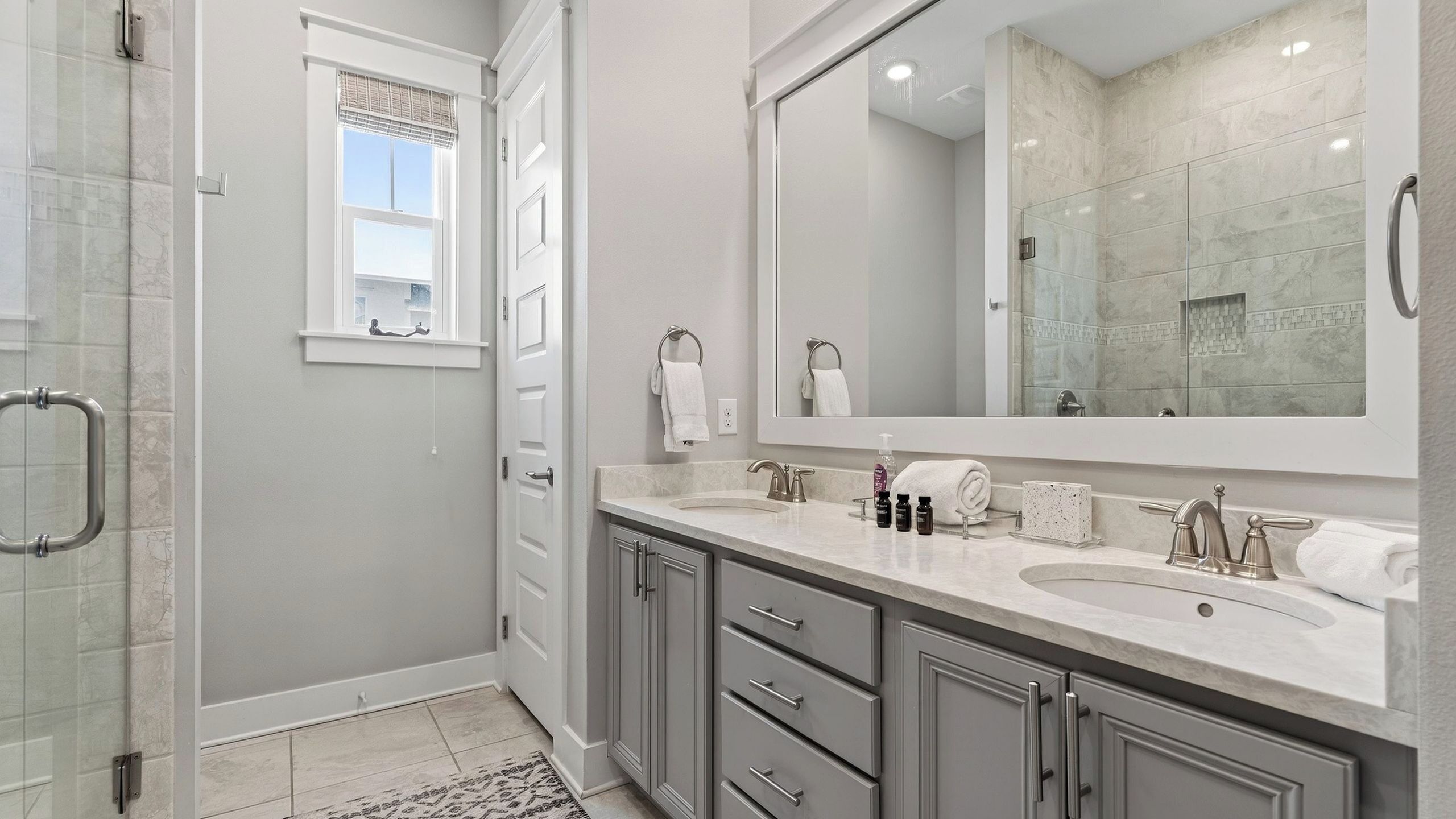 Une salle de bain moderne avec deux lavabos, un grand miroir et une douche à l’italienne.