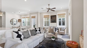 A modern living room with a white sofa, round coffee table, and a ceiling fan.