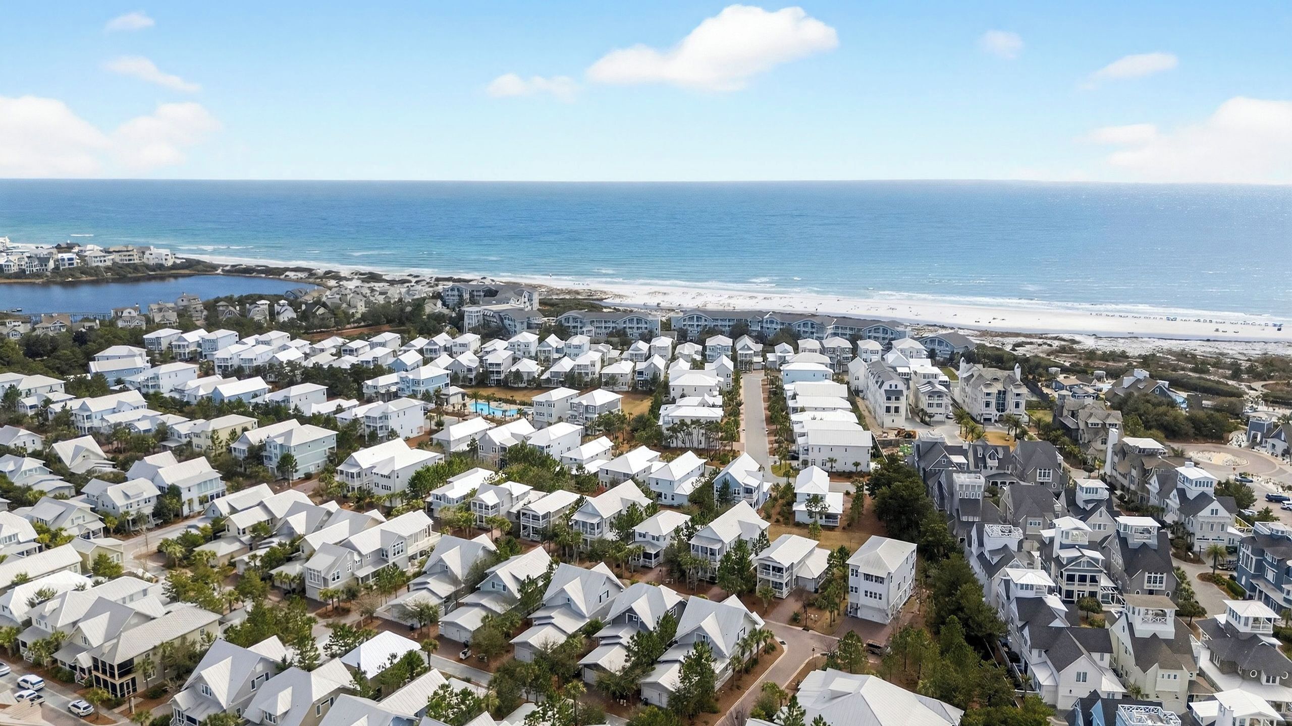A coastal residential area with houses, a beach, and a clear sky.