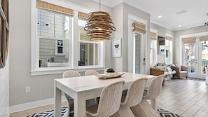 A dining area with a table, chairs, and a hanging light fixture.