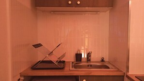A compact kitchen with a microwave, a sink, and a utensil holder on the countertop. - Sunset Lovers - WiFi - Netflix - Cosy atmosphere (Nancy)