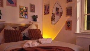 A hotel room with a bed, pillows, a bedside table, a plant, and wall art. - Sunset Lovers - WiFi - Netflix - Cosy atmosphere (Nancy)