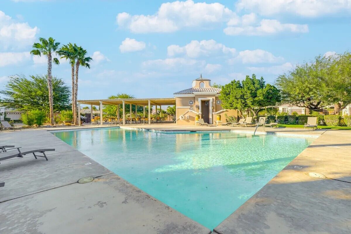 Una piscina con área techada y palmeras.