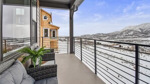A balcony with a view of a snowy landscape and a wooden structure. - Jordanelle Ridge Luxury Retreat (Heber City)