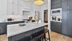 A modern kitchen with a central island, dark grey cabinets, and gold pendant lighting. - Jordanelle Ridge Luxury Retreat (Heber City)