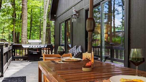 Un espace extérieur aménagé pour les repas, avec une table en bois, des chaises et un barbecue.