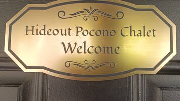 A brass welcome sign with the text "Hideout Pocono Chalet Welcome".