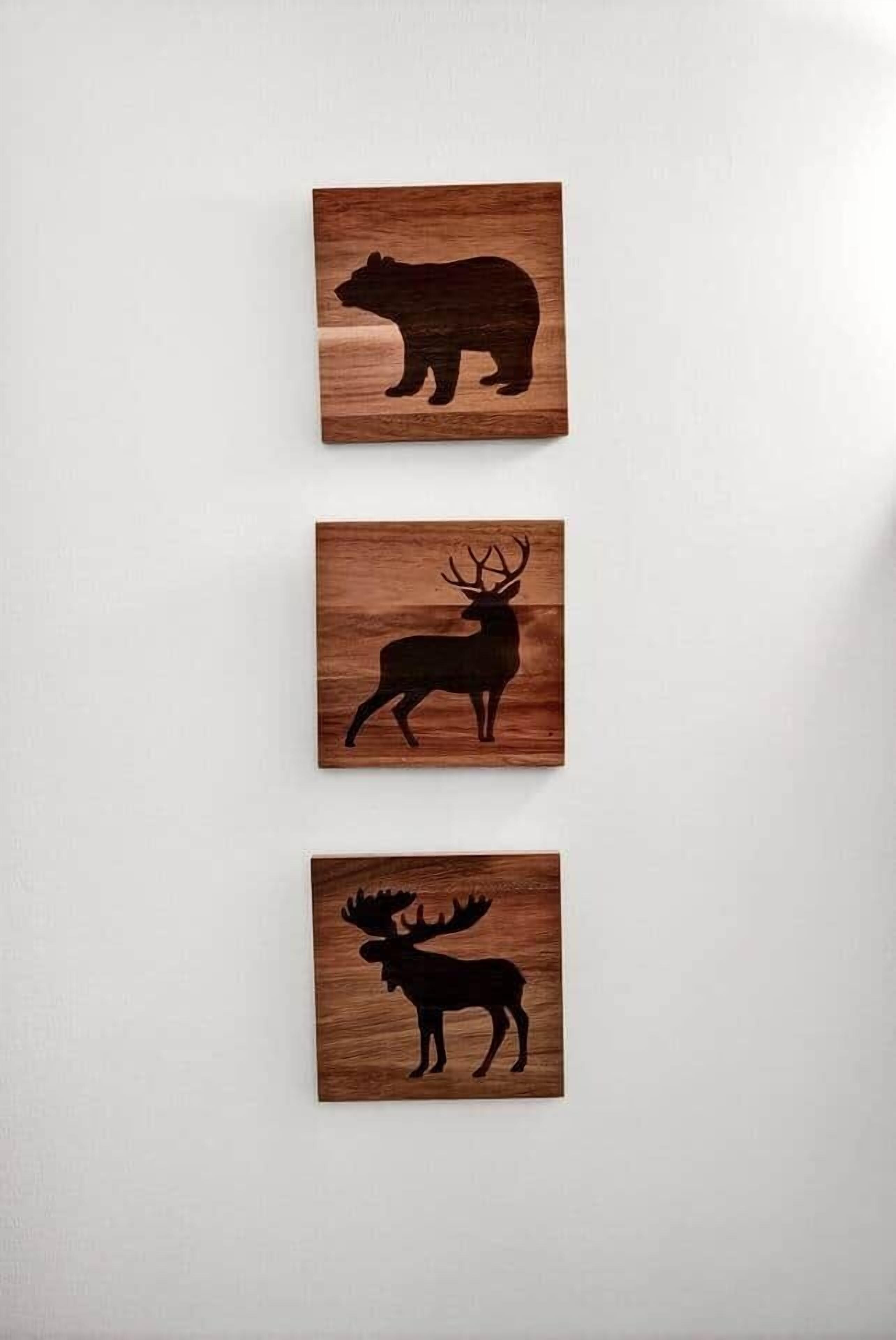 Three wooden panels with animal silhouettes: a bear, a deer, and a moose.