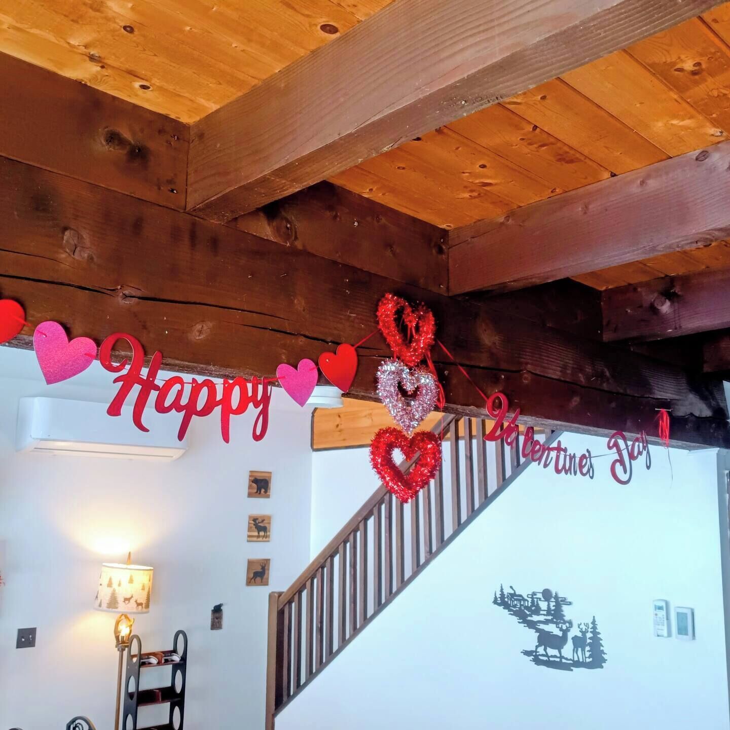 Et træinteriør med trappe, en væg med 'Happy Valentine's Day'-pynt og en lampe.