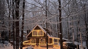 Une cabane aux murs en bois, entourée d’arbres couverts de neige.