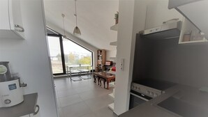 A modern kitchen with a Bosch dishwasher, a dining area with a table and chairs, and a large window providing a view of the outside. - Holiday Home in Kladno With Private Pool (Lany)