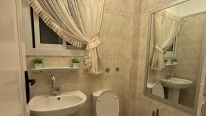 Un baño con lavamanos, inodoro y espejo.