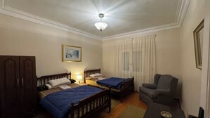 Una habitación con dos camas individuales, un sofá, un escritorio y un armario.