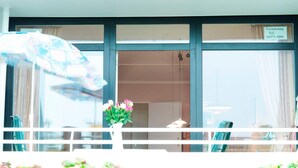 Een hotelkamer met een balkon, uitzicht op de straat en een bord met een telefoonnummer.