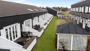 A row of white cabins with dark roofs, arranged in a linear fashion along a narrow grassy path. - Gorgeous apartment in Vestervig (Vestervig)