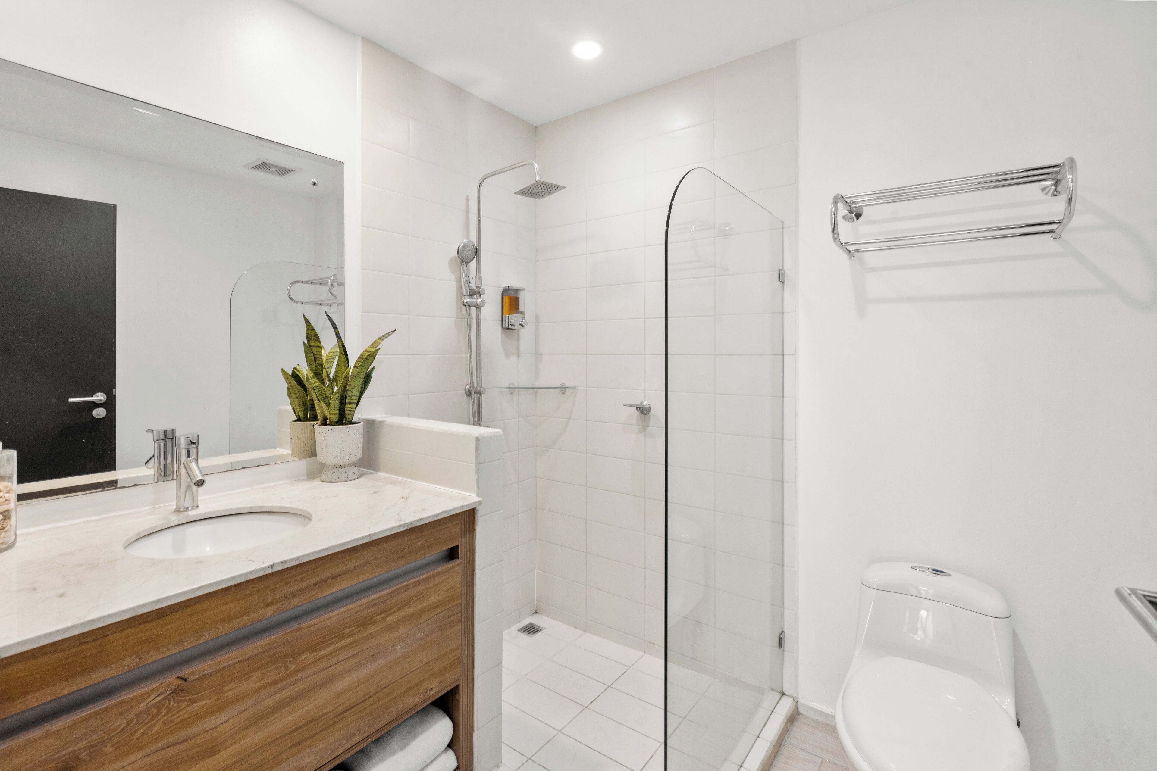 A modern bathroom with a wooden vanity, a glass shower enclosure, and a white toilet.