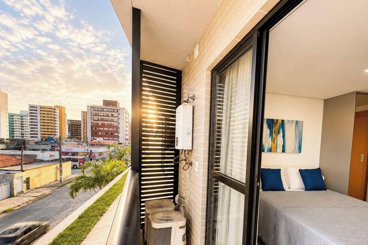 A balcony with a city view, a bed with blue pillows, and a radiator.