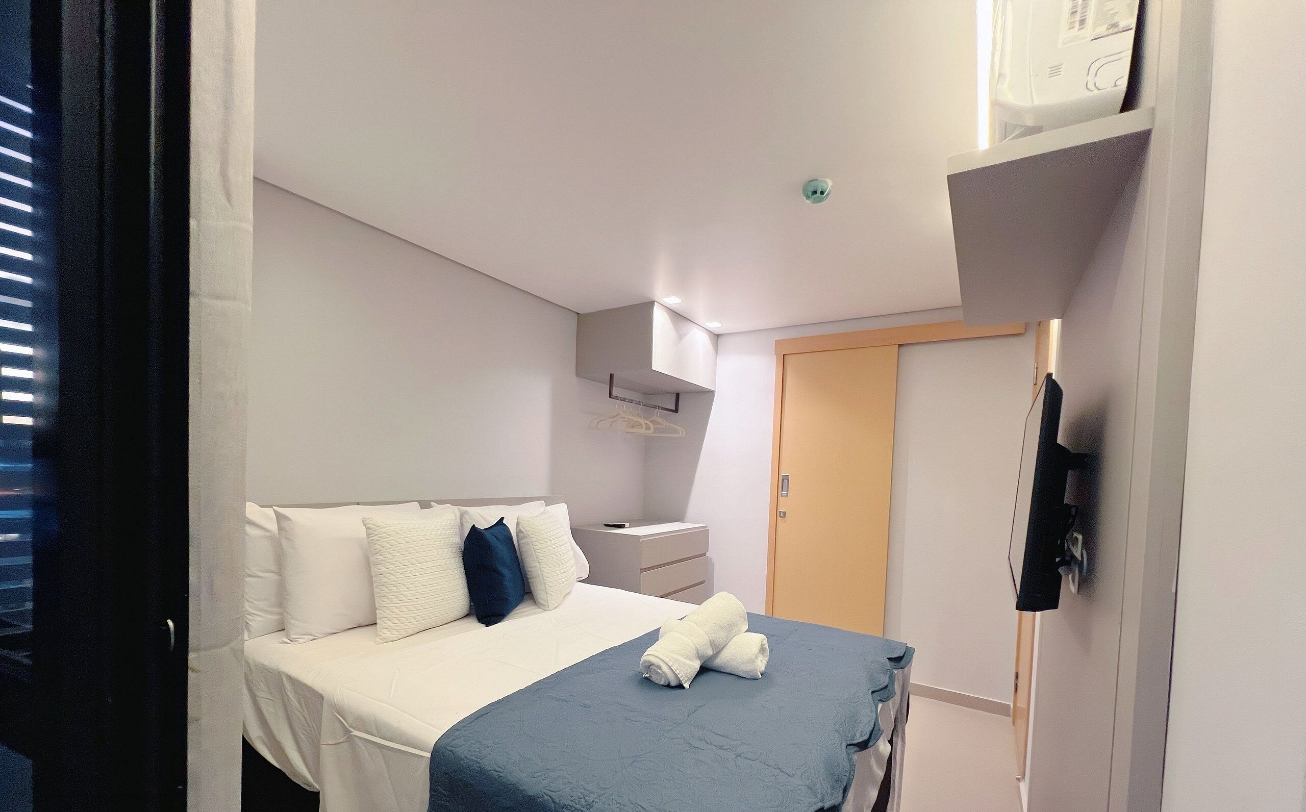 Una habitación de hotel con cama, mesita de noche y armario.