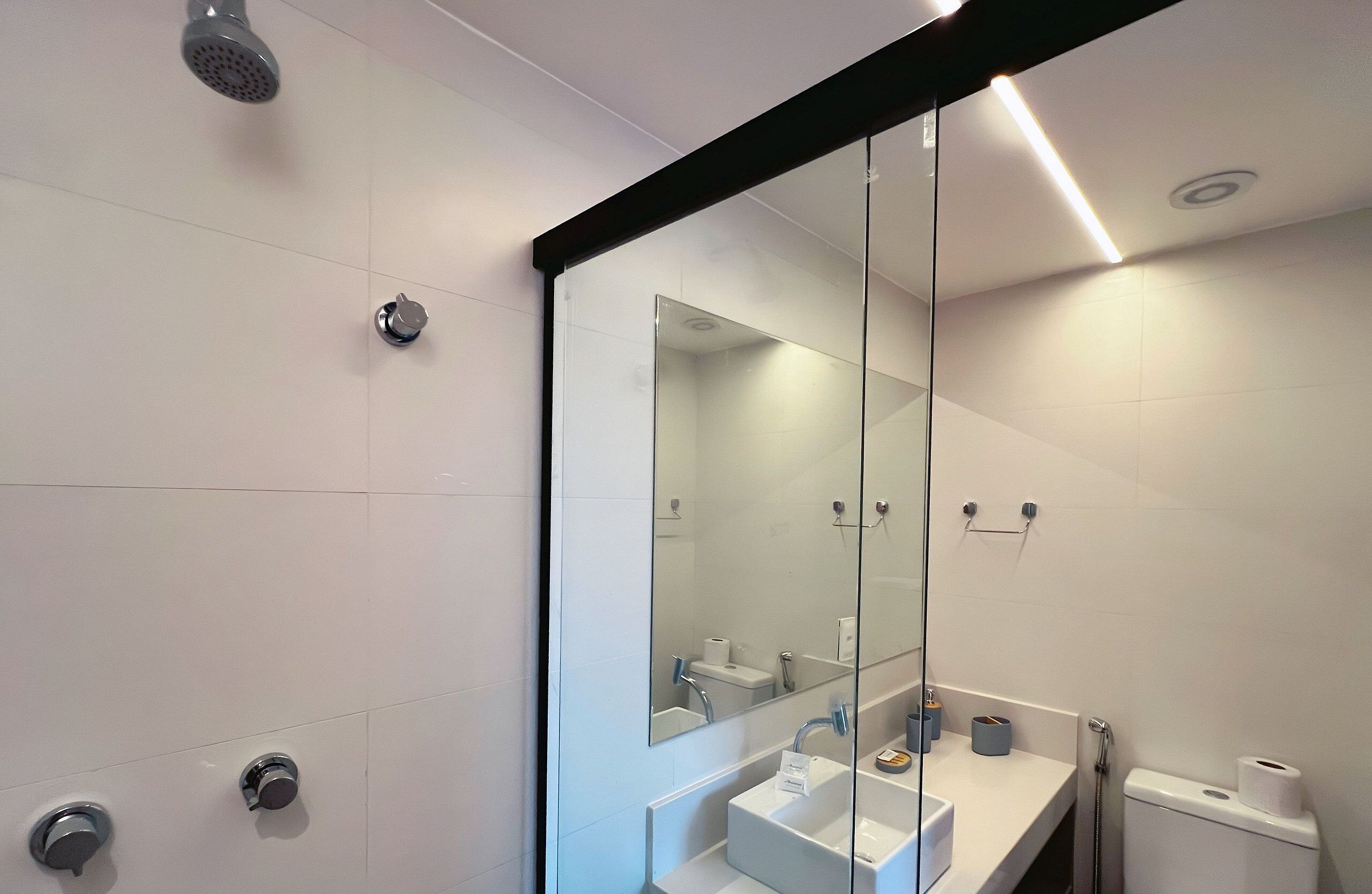 Un baño moderno con cabina de ducha de vidrio, un lavabo blanco y un inodoro.