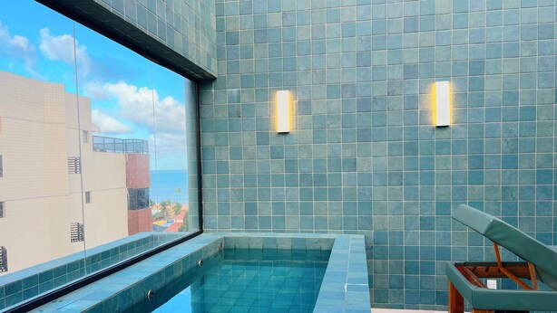 A modern indoor pool with a clear view of the sky and buildings through a large window. - Oceânica Cabo Branco (João Pessoa)
