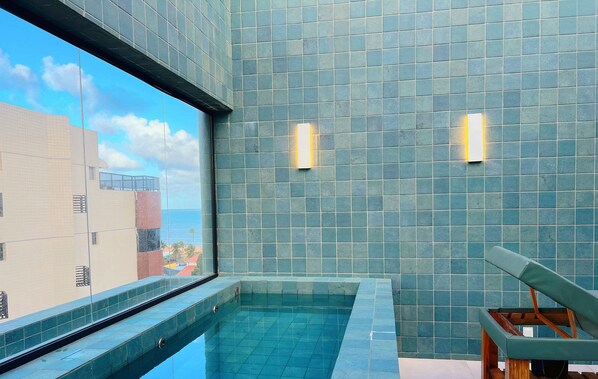Una piscina interior moderna con una vista despejada del cielo y edificios a través de un amplio ventanal.