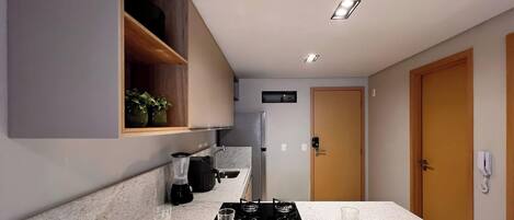 Una cocina moderna con estufa integrada, cafetera y refrigerador.