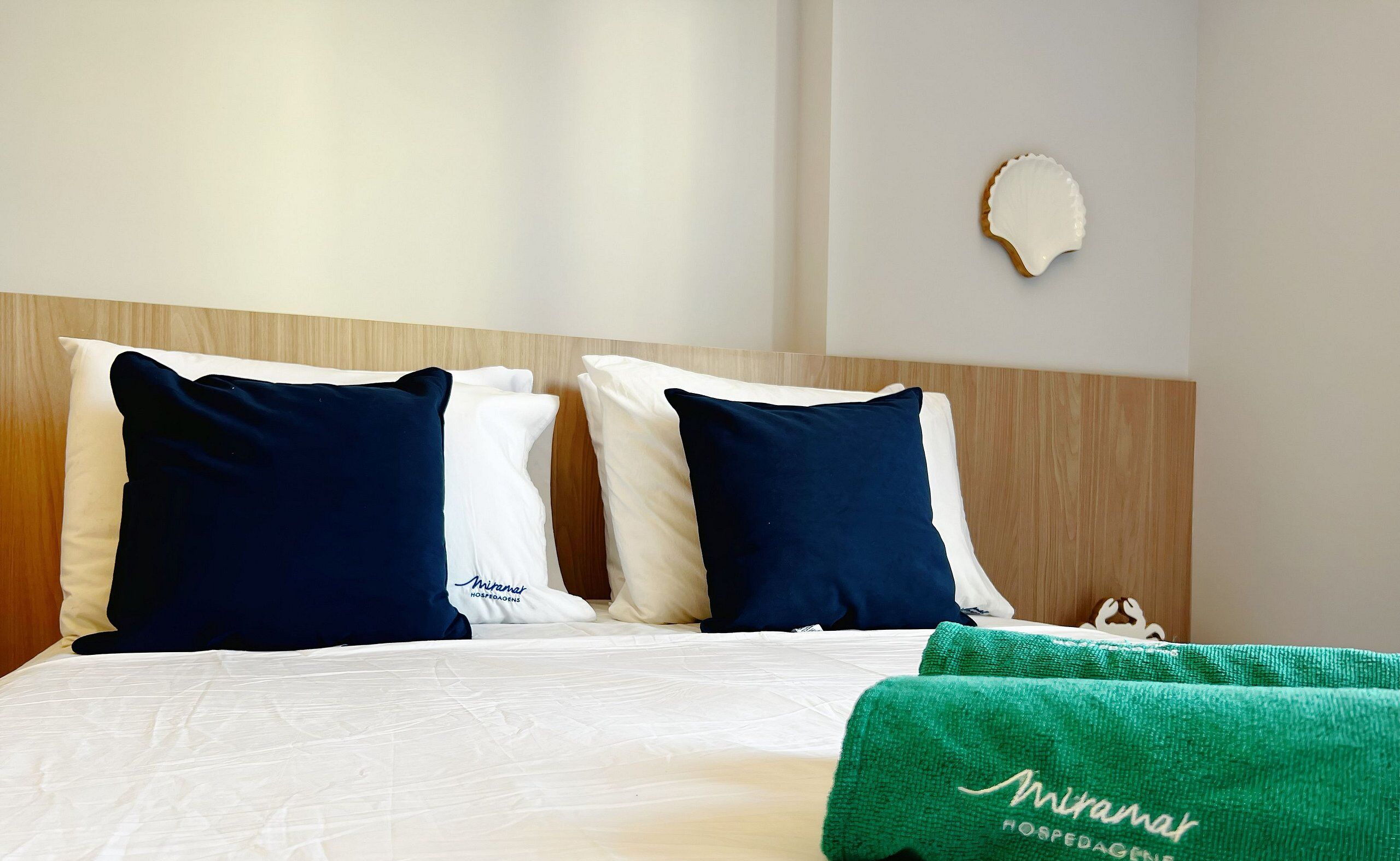 Een hotelkamer met een bed, twee kussens, een groene handdoek en een houten hoofdbord.