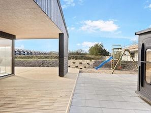 A modern building with a wooden deck and a playground with a slide.