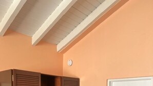 Een kamer met een houten garderobe, een witte deur en een plafond met houten balken.
