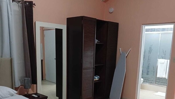 Een slaapkamer met een bed, een kledingkast, een spiegel en een deur naar een balkon.