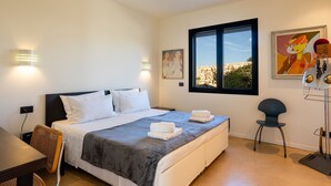 Un dormitorio moderno con una cama grande, dos mesitas de noche, un escritorio y una silla. Hay dos lámparas de pared y una ventana con vistas al exterior.