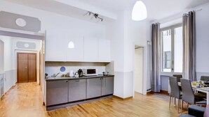 Une cuisine moderne avec des meubles blancs, un four à micro-ondes et un évier. On y trouve également un coin repas avec une table et des chaises.
