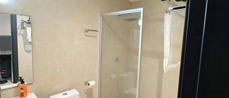 Un baño moderno con inodoro, lavamanos y ducha envuelta en vidrio.