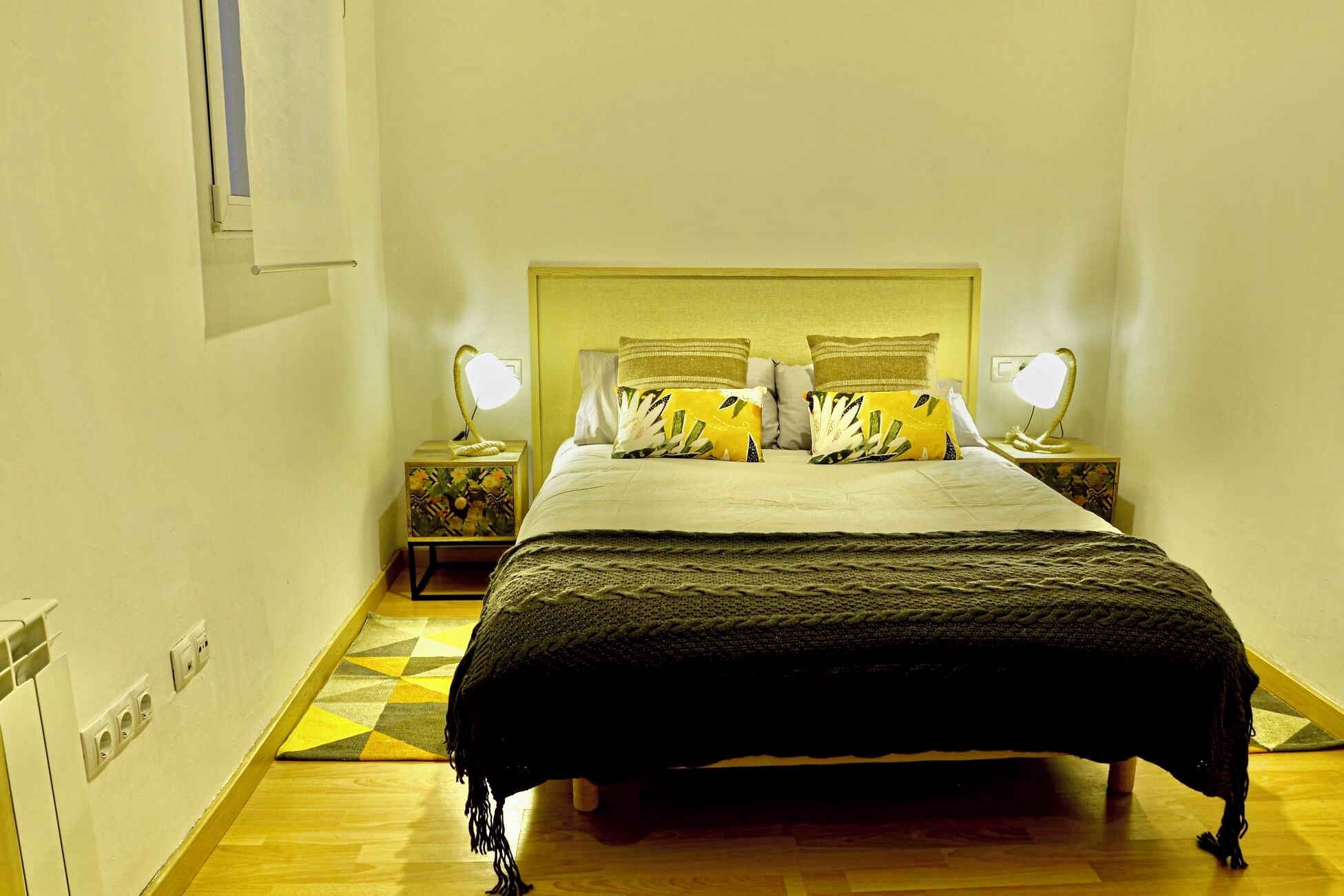 Une chambre à coucher bien rangée, avec un lit, deux lampes de chevet et un tapis à motifs.