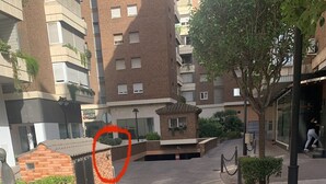 En bostadsgata med tydlig vägmarkering, byggnader i tegel och en liten tegelbyggnad med en grind.
