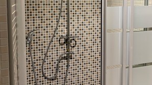 En duschkabin med en vägg som är beklädd med ett mosaikmönster i kakel och en glasdörr.