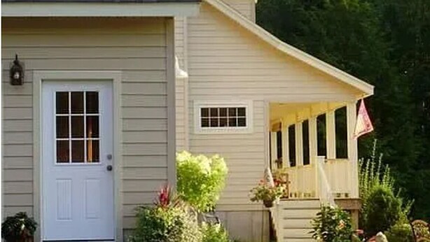 A two-story house with a front porch, a garage door, and a small window.