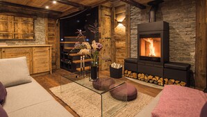 A cozy living room with a stone fireplace, wooden beams, and a modern glass coffee table.