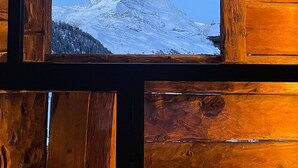 A wooden cabin with a window revealing a snow-capped mountain peak.