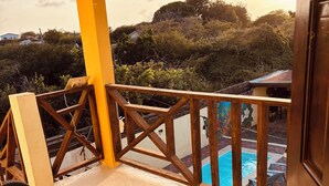 A balcony with a view of a swimming pool and surrounding greenery. - Sol appartments with pool (Willemstad)