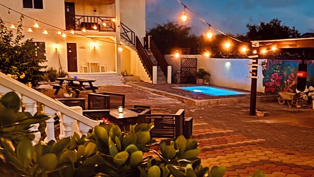 A pool area with string lights, a staircase, and a patio with tables and chairs. - Sol appartments with pool (Willemstad)