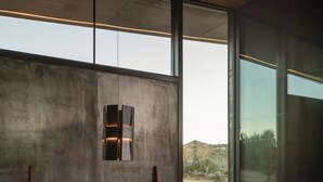 A modern interior with a wooden ceiling, large windows, and a minimalist dining area. - Obsidian - Industrial-Modern Villa (Yucca Valley)