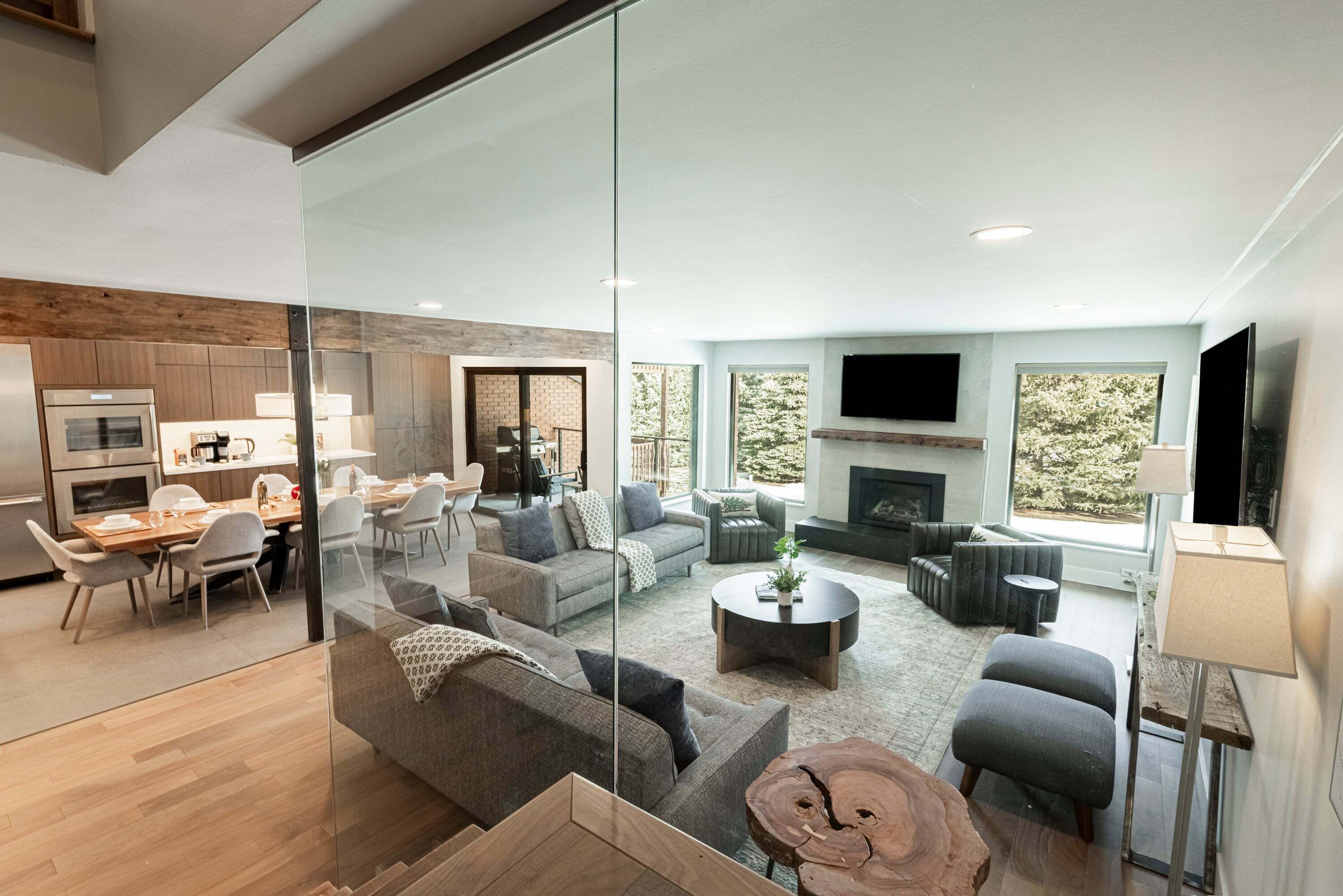 A modern living room with a fireplace, a dining area, and a kitchen with a built-in oven.