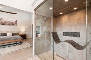 A modern bathroom with a glass-enclosed shower, a wooden bench, and a bed with a headboard. - Spacious 4BR Townhome with Private Hot Tub, Theater Room & Home Gym, Walk to Canyons Village (Park City)