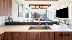 Une cuisine moderne dotée d’un grand îlot central, de meubles en bois et d’une grande fenêtre offrant une vue sur l’extérieur.