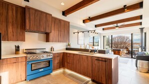 Une cuisine moderne avec des meubles en bois, un four bleu et un grand îlot central.